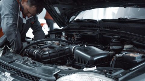 Mechanic inspecting a car engine beneath the raised bonnet